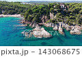 An aerial view of a drone flies over the beach, sea and coastal cliffs near Santa Clotilde Park on a sunny day in the tourist town of Lloret de Mar, Catalonia, Spain 143068675