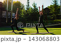 Elderly women practicing slow motion Pilates lunges outdoors on yoga mats, improving balance 143068803