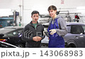 Young man car mechanic talks with man client in workshop and takes order. 143068983