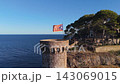 The flag of Catalonia flies on the tower of a fortress on the seashore at sunset on a sunny day in the tourist town of Tossa De Mar, Catalonia, Spain 143069015