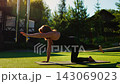 Elderly women practicing gentle Pilates on yoga mats in a serene outdoor garden, performing slow 143069023