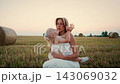 Tender mother and daughter bonding in a golden harvested field at sunset, sharing affectionate 143069032