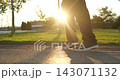 Kid walks along park path at sunset. Close-up of schoolchild legs and sneakers in warm evening light represents independence, outdoor activity, childhood, daily routine and healthy active lifestyle 143071132