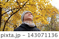 Kid observes golden autumn canopy in park with calm expression. Peaceful scene evokes mindfulness, curiosity, seasonal beauty, outdoor relaxation and appreciation of nature. 143071136
