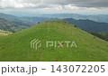 Green Pyrenean Mountain Ridge with Two Hikers Beneath Dramatic Clouds 143072205