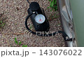 Portable tire inflator connected to vehicle wheel for pressure check on gravel surface near outdoor wall 143076022