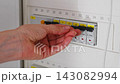 hand interacting with electrical switches in a residential indoor setting, neutral focused task, close-up steady shot, plastic and metal materials, white and black colors. 143082994