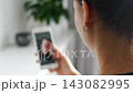 Woman scrolling social media on a smartphone at home. Digital addiction concept with endless content consumption and screen time. 143082995