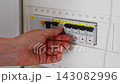 switching off a circuit breaker in an indoor electrical panel, safety-focused close-up shot for home improvement and electrician services tips, neutral, focused on safety and maintenance. 143082996