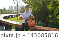 Schoolboy sits on bench in sunny school park, putting water bottle into orange backpack. Outdoor student routine shows independence, healthy habits, hydration, organization and everyday school life 143085816