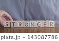motivational word Stronger, laying out by hand from letters on wooden cubes, slow motion 143087786