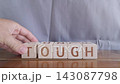 motivational word Tough, laying out by hand from letters on wooden cubes, slow motion 143087798
