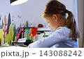 First grade girl practices handwriting at desk in her room. Child studies at home at beginning of school year with selective focus and soft background 143088242