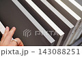 Woman touches countertop samples while choosing material in furniture showroom. Home renovation and interior design choice captured with selective focus and shallow depth of field 143088251