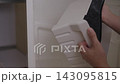 Housekeeper performing house chores by wiping and placing clean plastic container drawer inside fresh, empty freezer, ensuring proper hygiene and maintenance in kitchen, close-up, slow motion. 143095815