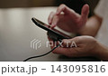 Male hands holding mobile device with external cooling system attached, using phone, playing video games and navigating user interface by tapping and swiping on screen, close-up, slow motion. 143095816
