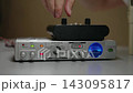 Close-up of hand adjusting knobs on professional audio equipment. Sound engineer, producer fine tunes settings on preamp and interface in recording studio. Concept of technical adjustments. 143095817