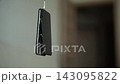Broken black smartphone with detached screen hanging from cable, slowly spinning. Concept of internal parts, repair, e-waste, technology breakdown, planned obsolescence. Blurry background, nobody. 143095822