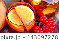 Autumn Picnic Table With Tea, Orange Slices and Red viburnum berries, traditional bagels and colorful forest backdrop create inviting seasonal setting 143097278