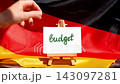 Paper note with words BUDGET on National symbol of Germany. German wave silky flag background. Economy federal annual finance planning 143097281