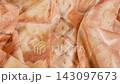 Orange silk fabric falls smoothly in slow motion against a bright white background. Macro shot captures the delicate texture and elegant patterns of the moving textile. 143097673
