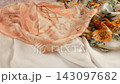 Lightweight plain silk scarf falls gently onto a pile of floral fabrics in slow motion. The pastel peach and orange colors look elegant and professional.  143097682