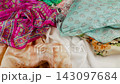 Colorful printed silk fabric falling onto colorful textile background in slow motion. Oriental floral and paisley pattern details close up. Luxury texture ideal for fashion and apparel industry. 143097684