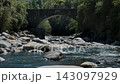 Slow-motion footage of alpine water moving past arched bridge under summer sunshine 143097929