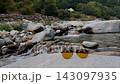 Close up of eyewear left on rock near alpine riverbank during summer getaway 143097935