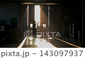 Industrial worker operating heavy machinery inside dim storage building near open doors 143097937