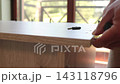 Extreme close up of male hand screwing metal fastener pin into wooden board for DIY desk assembly, handyman assembling wooden furniture at home 143118796