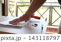 Close up of man hands unfolding instruction manual and preparing screwdriver with screws for DIY furniture assembly at home, handyman preparing tools for furniture repair work on wooden table 143118797