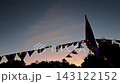 Colorful festive bunting flags and string lights flickering against dusk sky during outdoor evening celebration event.	 143122152