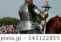 Medium shot from behind captures jouster in articulated plate armor and black cap seated firmly in decorated saddle while grasping long tournament spear ready for lists duel.... 143122855