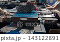 Close up shot reveals textile factory workers placing knitted grey work gloves onto metal shaping molds. Industrial manufacturing line processes protective hand wear during busy production shift. 143122891