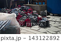 Worker tosses fresh bundle of protective gloves onto growing pile beside production line. Large accumulation reflects continuous output and bulk manufacturing inside glove factory. 143122892