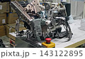 Worker guides knitted protective glove onto rotating machine for cuff processing. Manual control helps keep fabric aligned during industrial finishing. 143122895