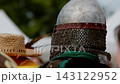 Closeup portrait shot captures medieval warrior in steel dome helmet with face bar grill and chainmail aventail standing among crowd before foot combat tournament. 143122952