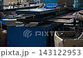 Tracking view reveals operators seated beside aging conveyor, repeating glove fitting tasks on metal molds. Simple machinery and modest factory setup convey budget focused textile manufacturing. 143122953