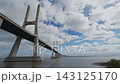 Vasco Da Gama Bridge Spans Wide River Under Cloudy Sky, Showing Modern Cable Stay Engineering And Calm Water Below. Bridge Arcs Toward Horizon In Lisbon. 143125170