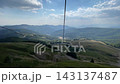 Empty chairlift hangs above forested mountain slope, with lift station visible uphill. Cable lift serves mountain visitors amid evergreen trees, open rocky terrain and distant ridge Kolasin ski resort 143137487