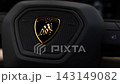 Close pan reveals a polished gold Lamborghini crest on a honeycomb insert inside the cabin, with shallow depth of field and low key lighting that emphasizes luxury detail. 143149082