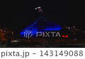 Aerial night view shows Latvian National Library in Riga during Riga Staro 2025. Blue LED wash, light mapping, pulsing crown, red heart lights, cars and street lamps. 143149088