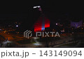 Riga Latvia, aerial wide shot of the Latvian National Library at night, vertical projections in red and blue white sweep the stepped facade, streets and cars visible 143149094