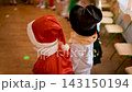 costume party holiday masquerade in kindergarten. santa claus with beard giving children gifts 143150194