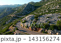 Empty winding road through rocky green mountain landscape 143156274