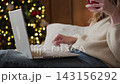 Woman using laptop with coffee during Christmas at home 143156292