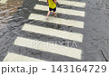 4K Person walking through flooded crosswalk with yellow umbrella 143164729