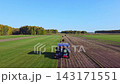 A tractor is working diligently in the fields under the warm sun on a beautiful sunny day 143171551