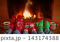 The family is sitting in front of the fireplace. People in clothes with Christmas ornaments are having fun at home. Slow motion 143174388